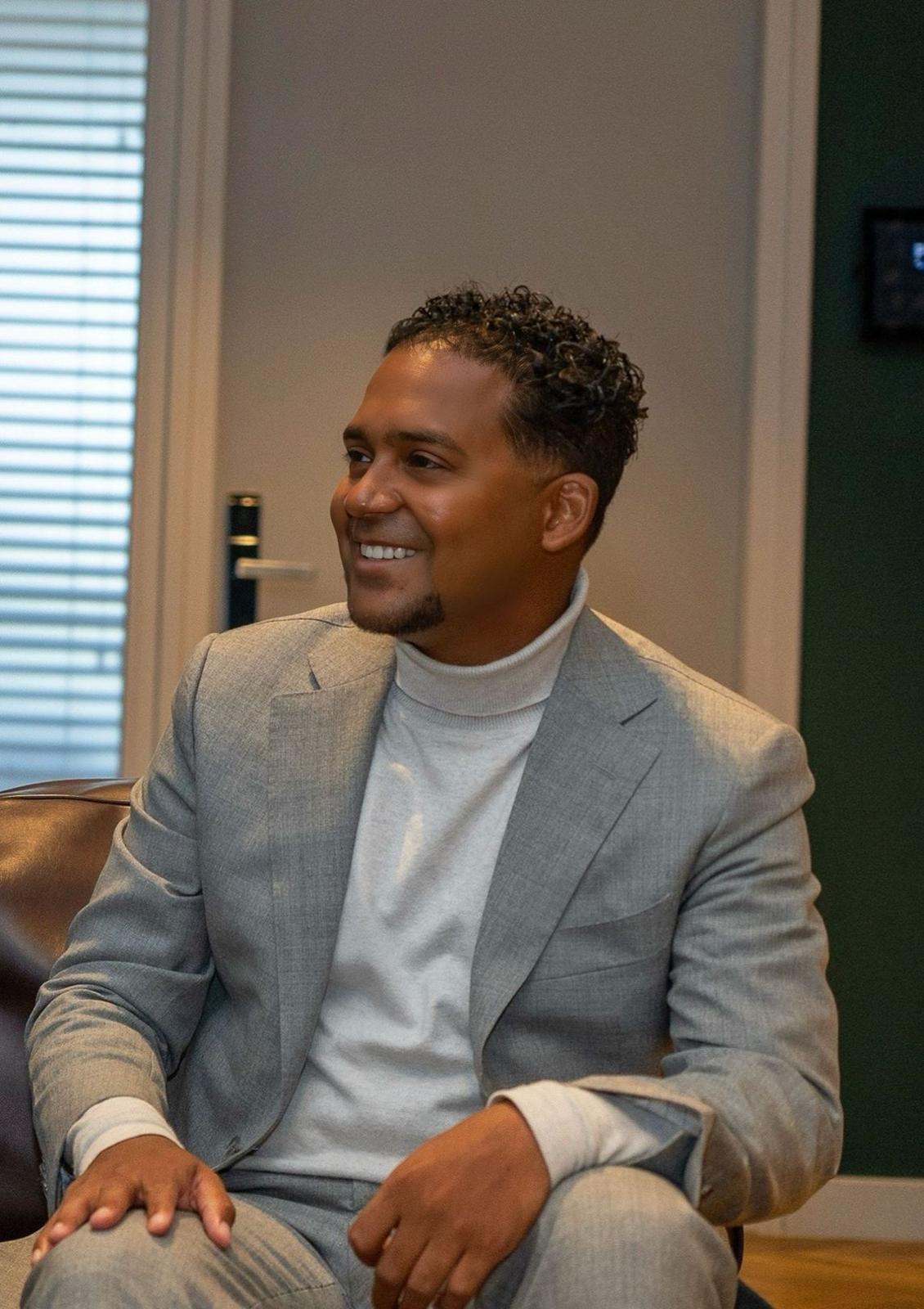 Professional portrait of woman with shoulder-length brown hair in charcoal business suit smiling confidently